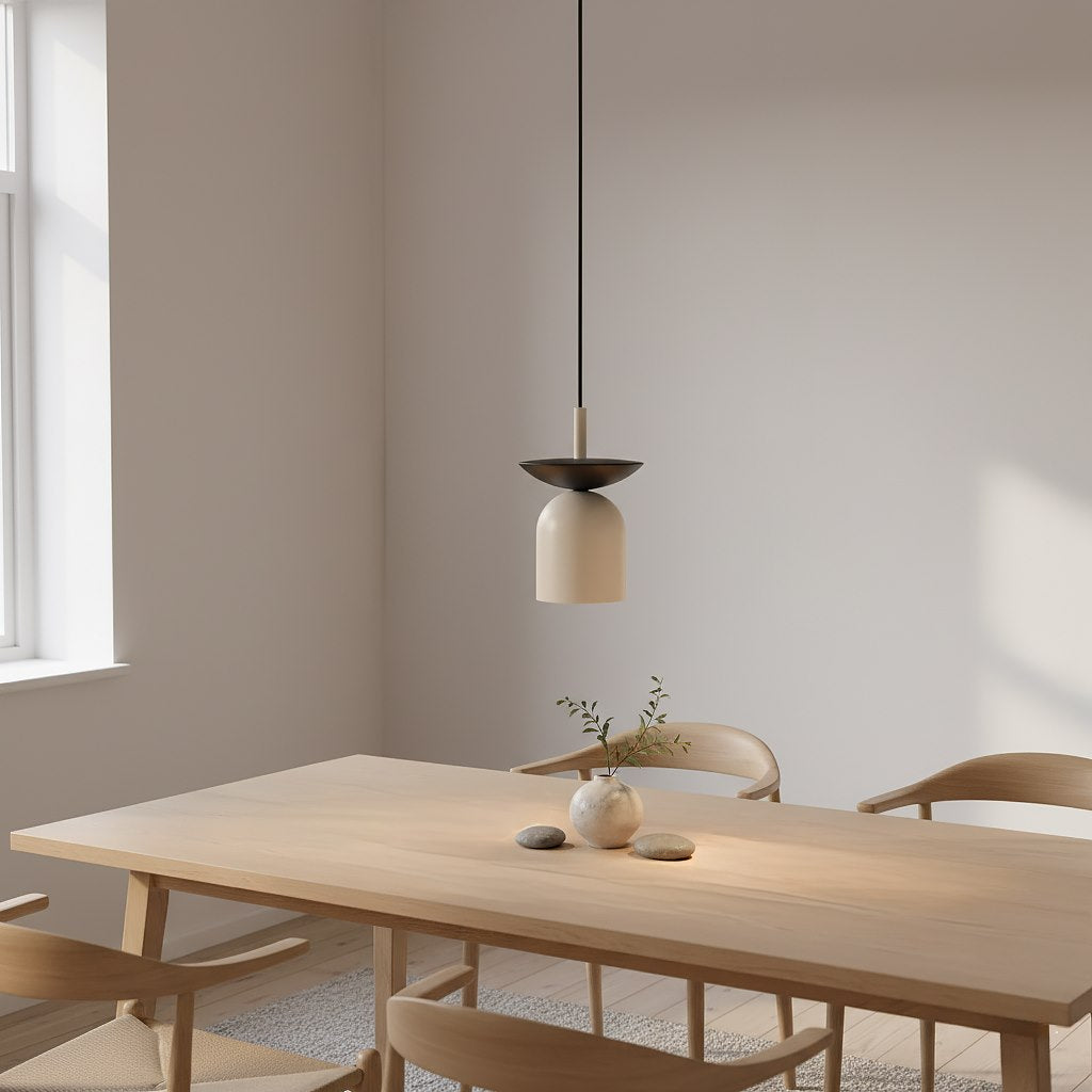 Beige hanglamp met donkere schotel boven een houten eettafel met houten stoelen in een lichte kamer