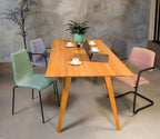 Vergaderstoel met zachtroze wolvilt bekleding en zwart sledeframe met armleuningen naast een houten tafel