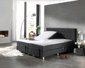 Wit topperlaken op een donkergrijze verstelbare boxspring met één opgeklapt hoofdeinde in een moderne slaapkamer