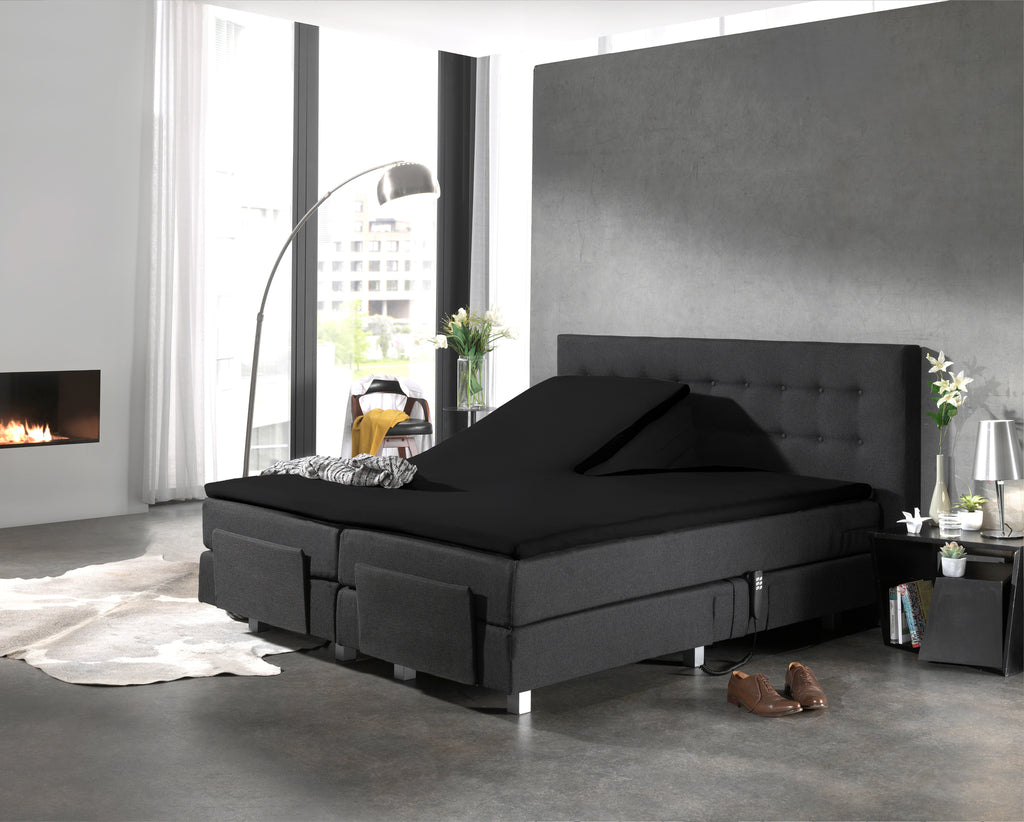 Zwart splittopper hoeslaken op een verstelbaar boxspringbed met antracietkleurig hoofdbord in een moderne slaapkamer