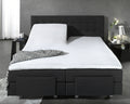 Wit molton hoeslaken op een gesplitste topper op een zwarte boxspring met een gestreepte plaid