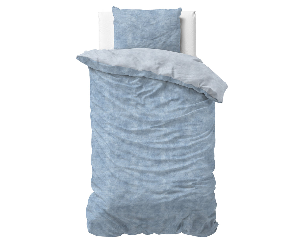 Blauw gewassen flanel dekbedovertrek met kussensloop op een bed, met omgeslagen rand in lichtere tint