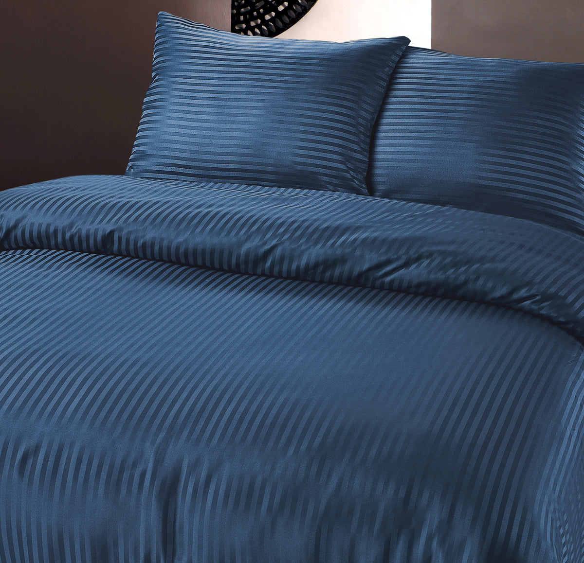 Marineblauw dekbedovertrek met geëmbosseerde hotelstrepen en twee bijpassende kussens op een bed