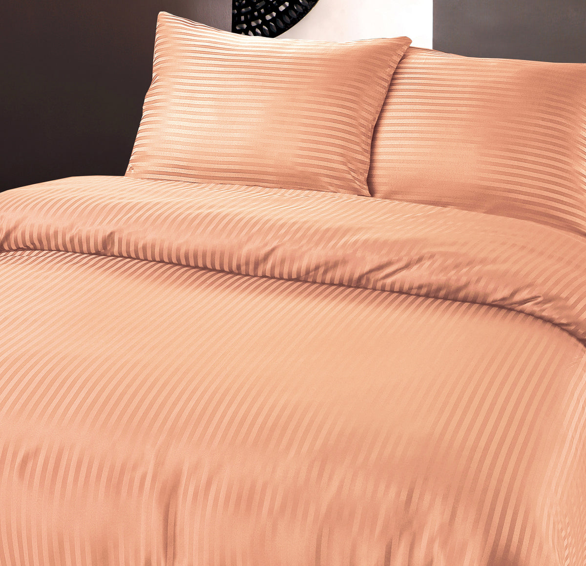Bed met pastel oranje dekbedovertrek en twee kussens met subtiele hotelstrepen