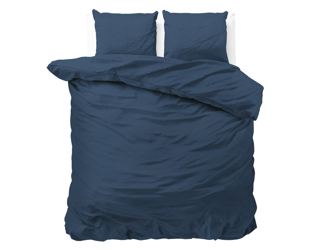 Marineblauw dekbedovertrek met twee bijpassende kussens op een bed, effen met subtiel geëmbosseerd effect