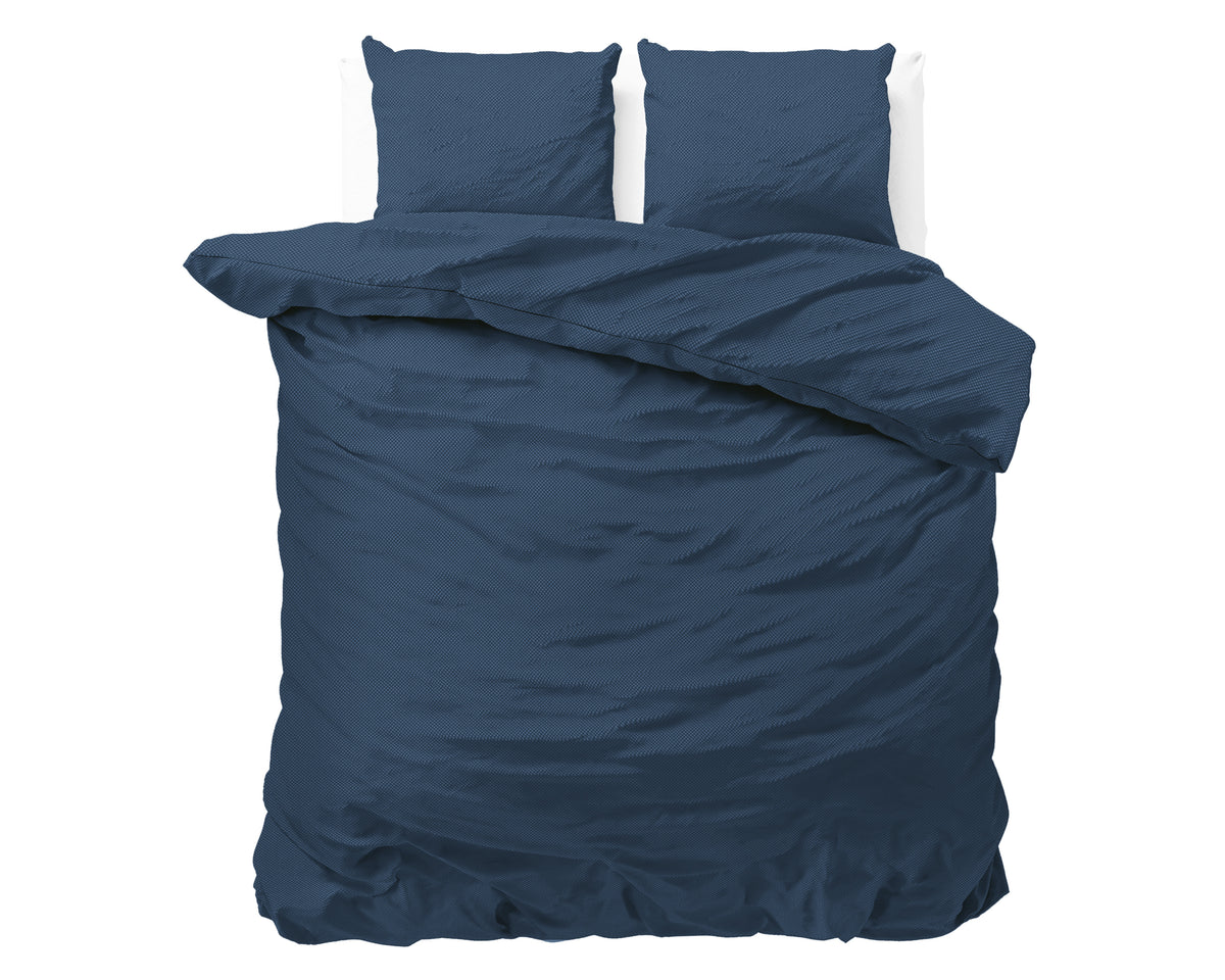 Marineblauw dekbedovertrek met twee bijpassende kussens op een bed, effen met subtiel geëmbosseerd effect