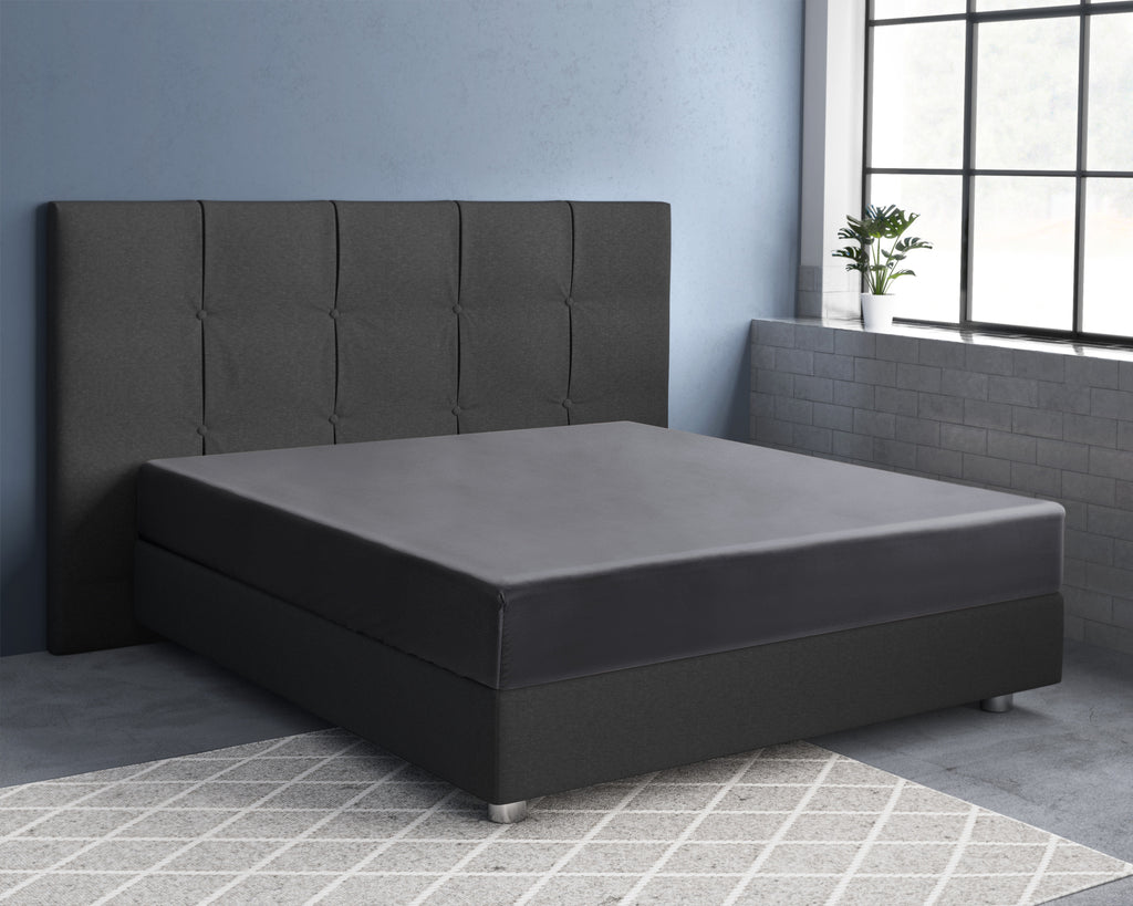 Antracietkleurig satijnen hoeslaken op een boxspring met gestoffeerd hoofdbord in een blauwgrijze slaapkamer