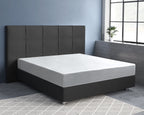 Wit hoeslaken over matras op donkergrijs boxspringbed met gecapitonneerd hoofdbord in kamer met blauwe muur