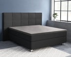 Donkergrijs boxspringbed met gestoffeerd hoofdbord en grijze topper in een slaapkamer met blauwe muur