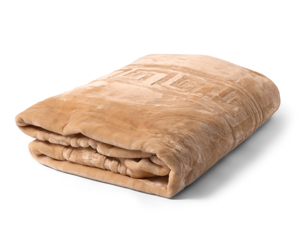 Opgevouwen beige fleecedeken met geëmbosseerd patroon langs de rand