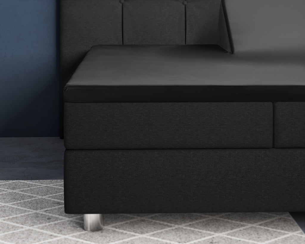 Zwart satijnen hoeslaken om een topper op een zwarte boxspring met gecapitonneerd hoofdbord