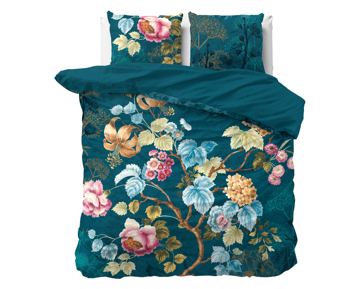 Blauw dekbedovertrek met kleurrijke bloemenprint en twee bijpassende kussens op een bed
