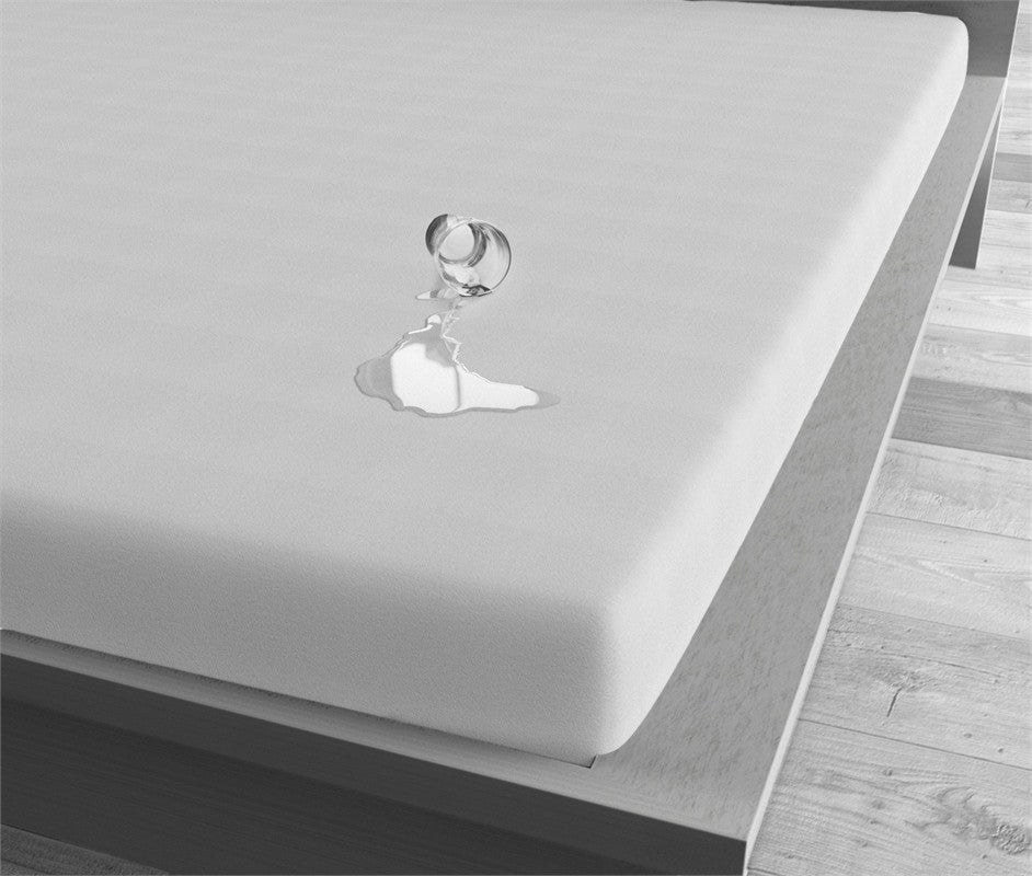 Wit waterdicht hoeslaken op een matras, met omgevallen glas waarvan het water op het laken blijft liggen
