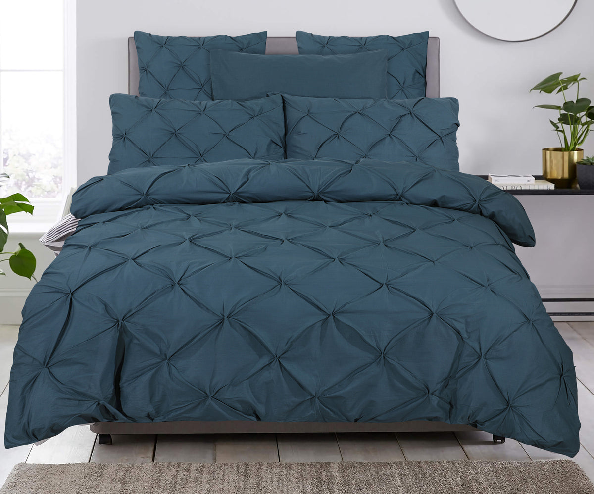 Blauw dekbedovertrek met pintuck-dessin en bijpassende kussens op een bed in een lichte slaapkamer
