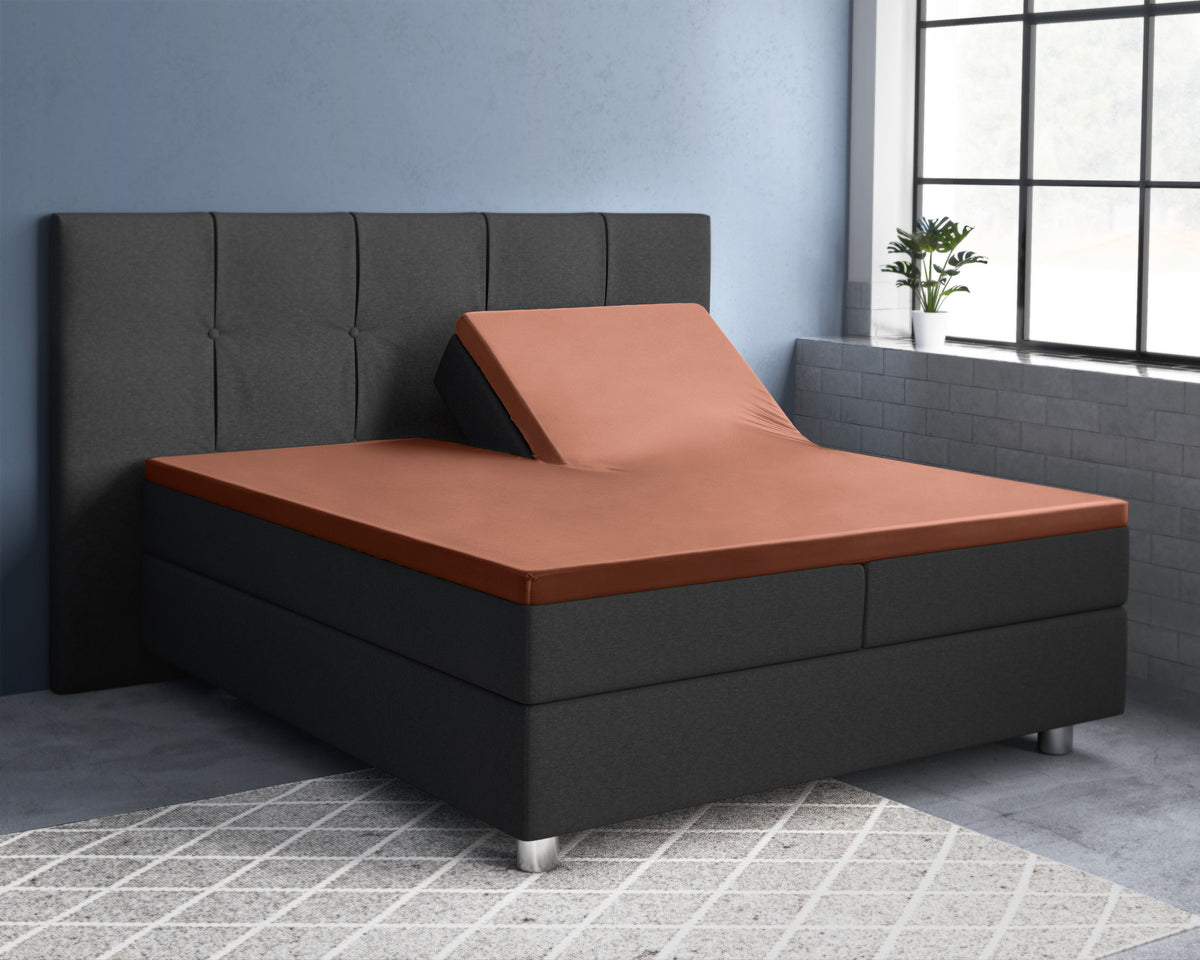 Bruin splittopper hoeslaken op een antracietkleurig boxspringbed, de ene bedhelft omhoog gezet