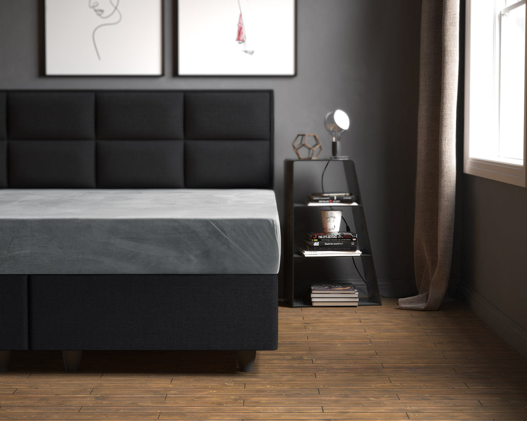 Grijs fluwelen hoeslaken op een bed met donkergrijs gestoffeerd hoofdbord in een slaapkamer met houten vloer