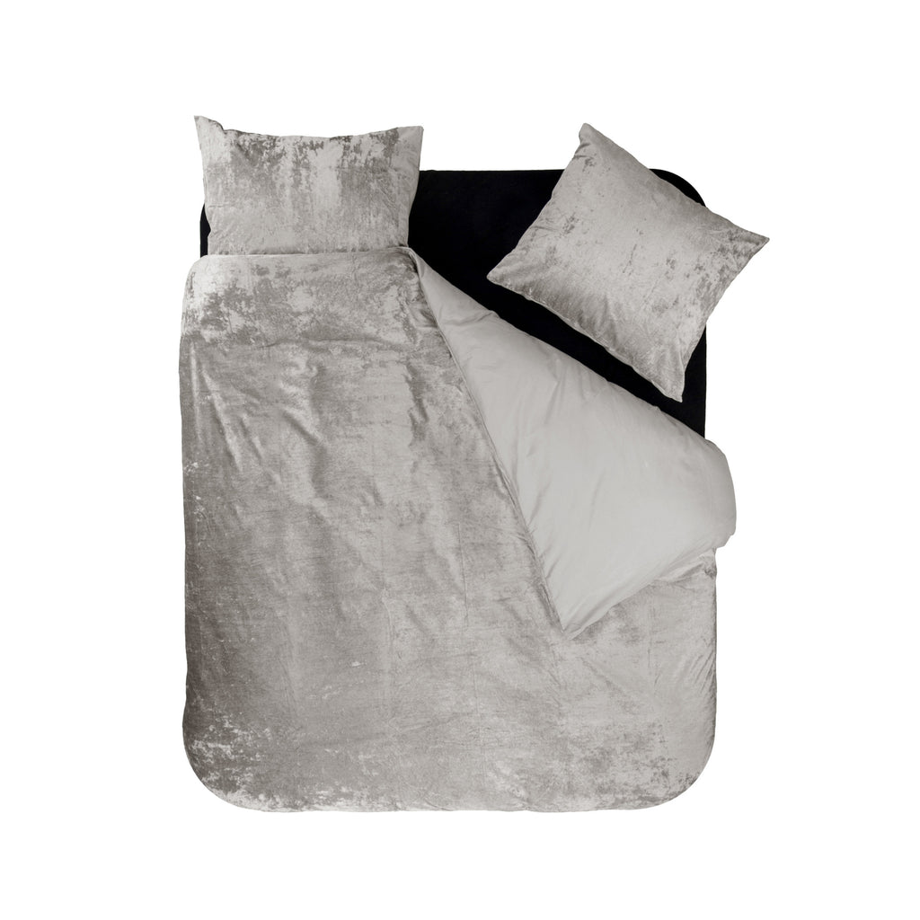 Dekbedovertrek van zandkleurig velvet met kristaleffect, deels teruggeslagen, met twee bijpassende kussens op een bed