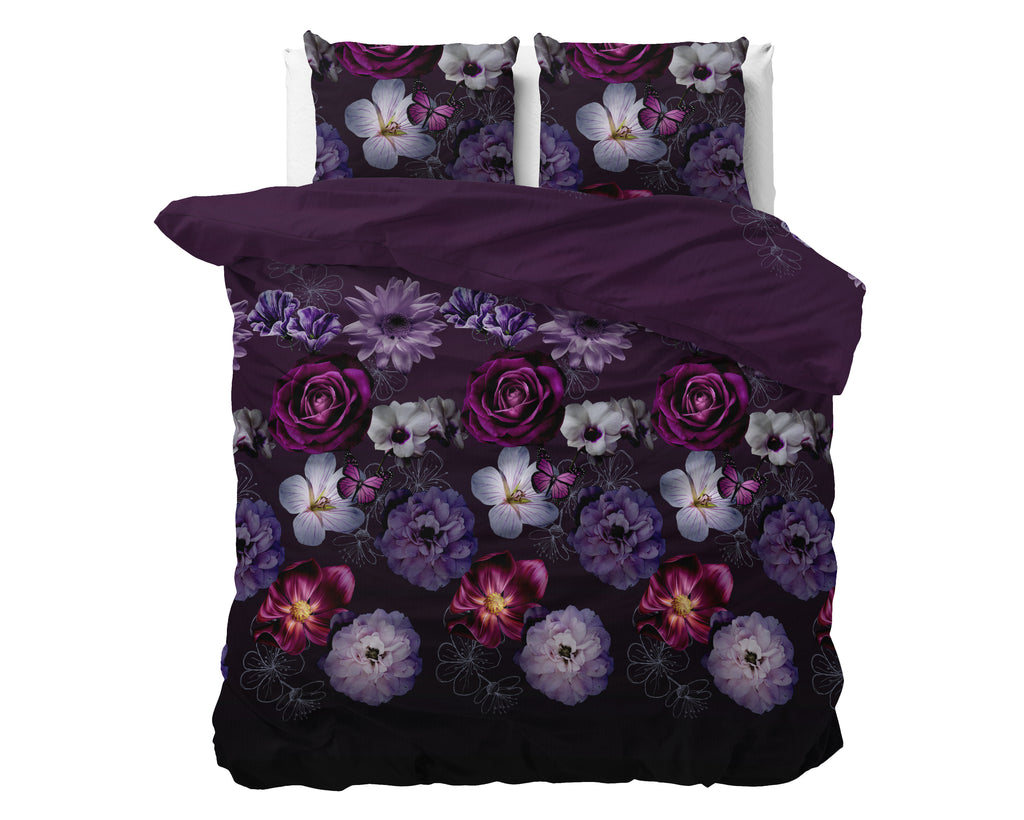Paars dekbedovertrek met bloemenprint van rozen en vlinders op een bed, met twee bijpassende kussens