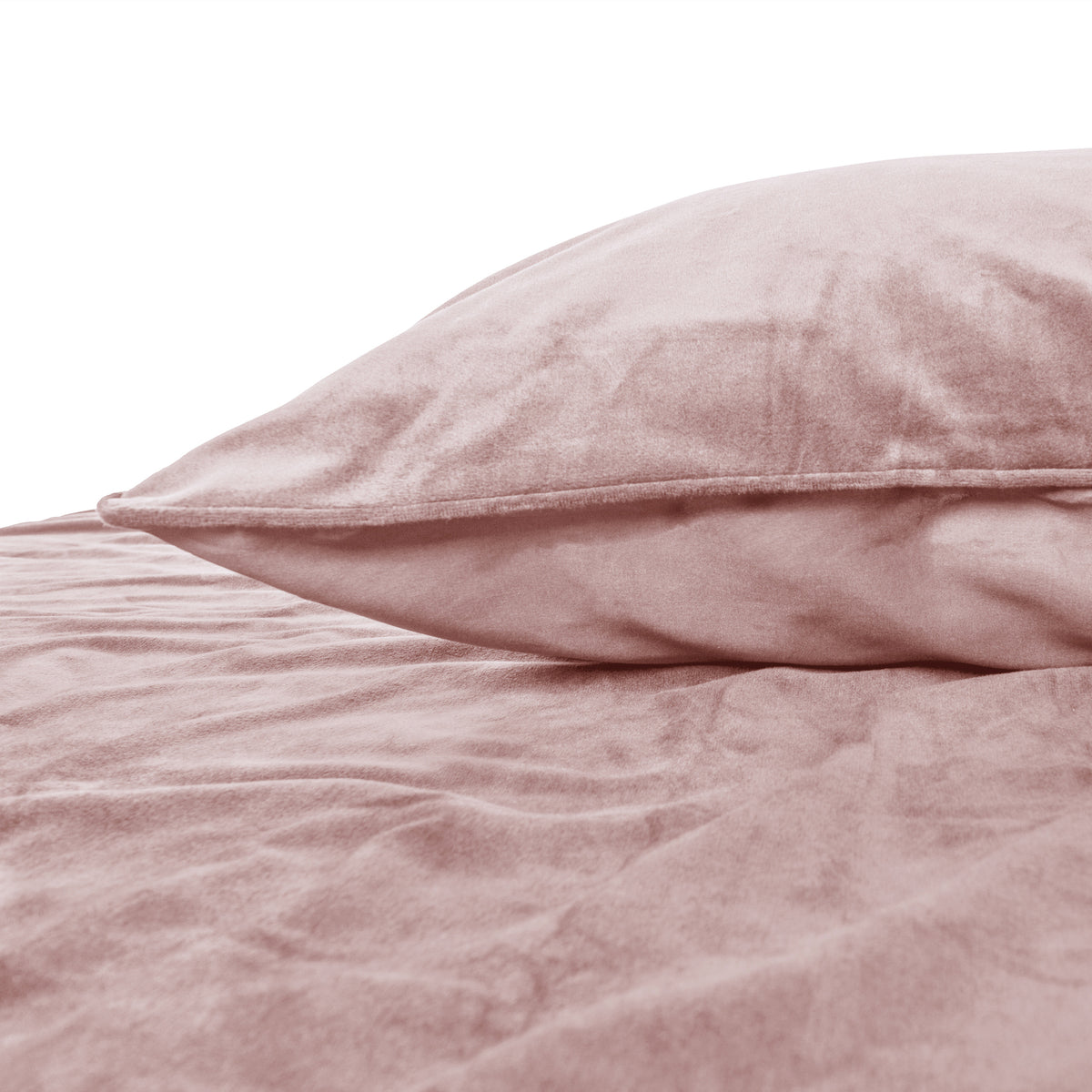 Roze fluwelen kussen met paspelrand op een bed met bijpassend roze fluwelen dekbedovertrek