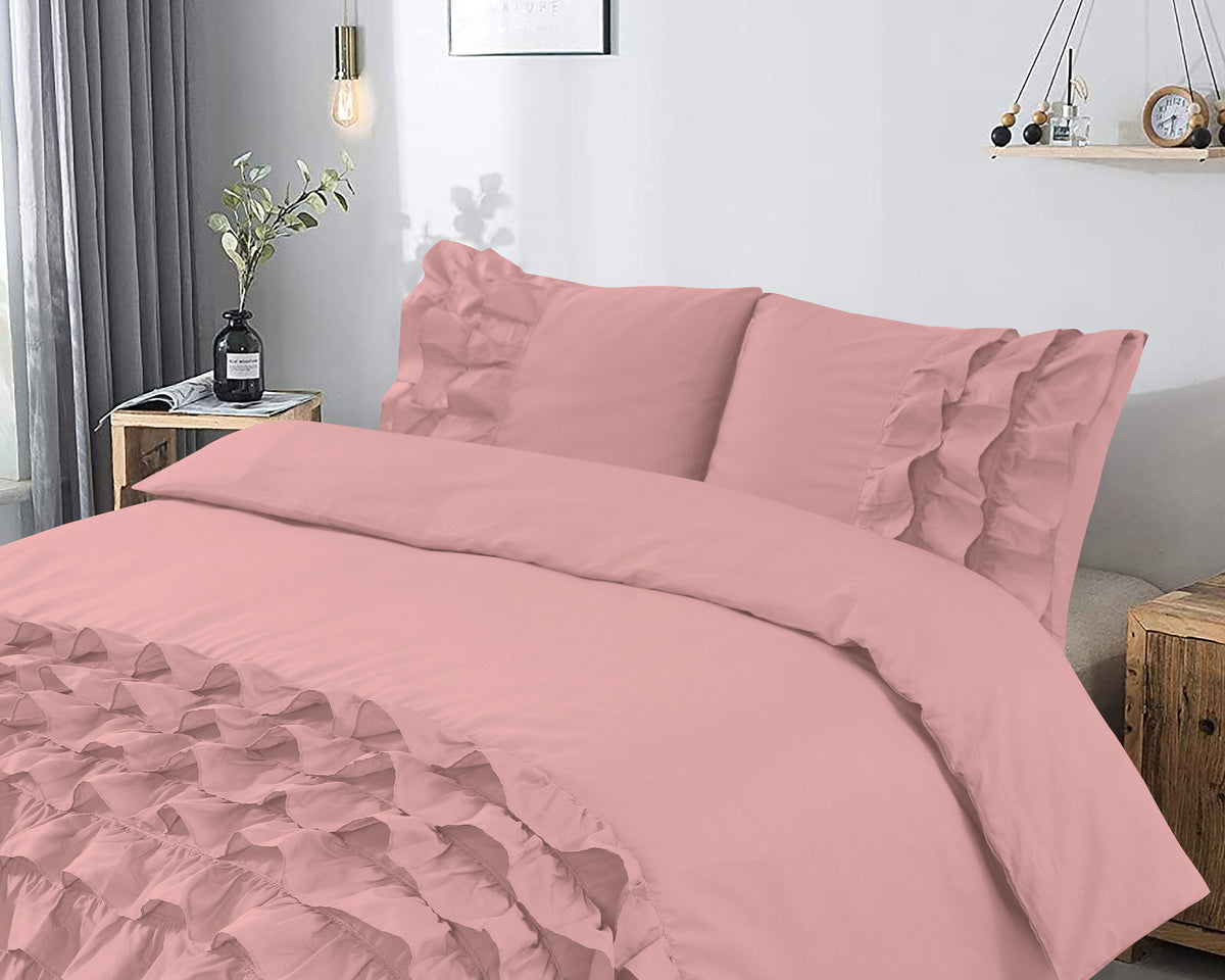 Roze dekbedovertrek met ruches en bijpassende kussenslopen op een bed in een lichte slaapkamer