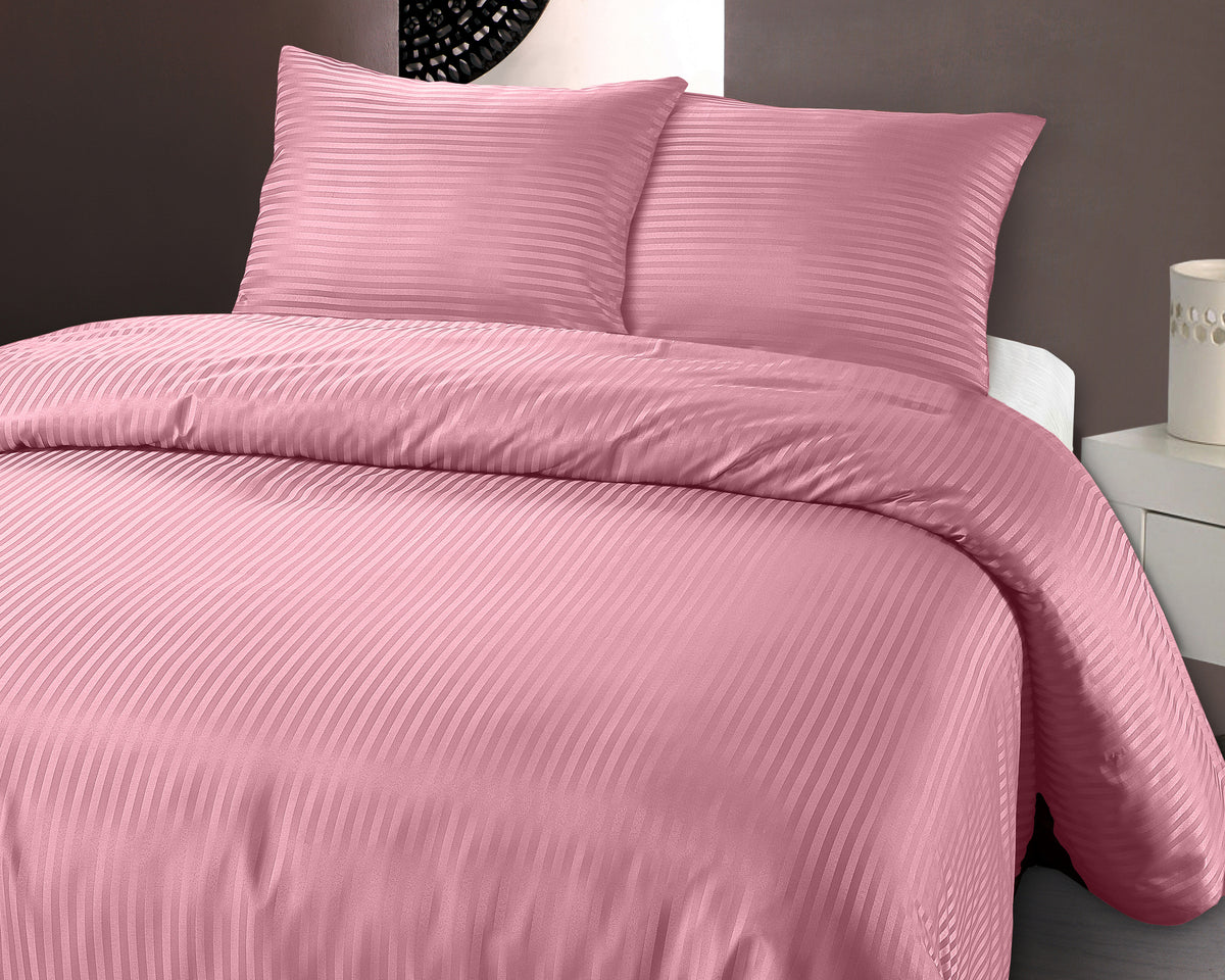Roze geëmbosseerd dekbedovertrek met fijne strepen en twee bijpassende kussens op een bed