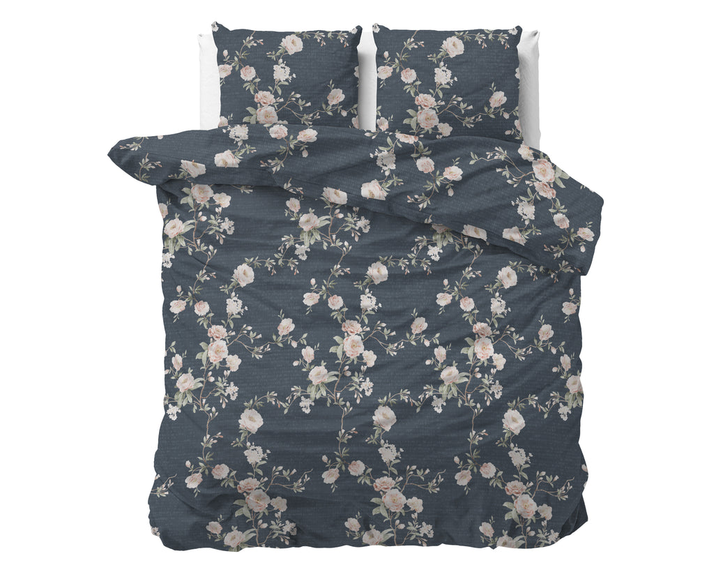 Indigo dekbedovertrek met roze en witte bloemenprint en twee bijpassende kussenslopen op een bed