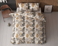 Bed met dekbedovertrek met palmbladprint in zand, goud, grijs en zwart, met twee kussens tegen een houten lamellenwand