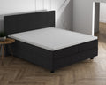 Wit topperhoeslaken op een matras van een donkergrijs boxspringbed met hoofdbord in een lichte slaapkamer