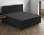 Antracietkleurig hoeslaken over een topper op een donkere boxspring met hoofdbord in een lichte slaapkamer