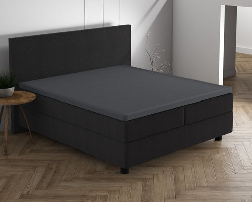 Antracietkleurig topper hoeslaken op een boxspring met hoofdbord in een slaapkamer met visgraatvloer