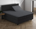 Antraciet hoeslaken op een split topper van een boxspring met donker hoofdbord op een visgraatvloer