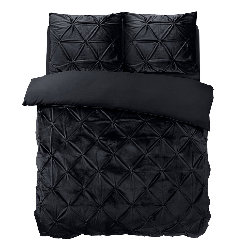 Zwart fluwelen dekbedovertrek met diamantvormig pintuck-motief en twee bijpassende kussenslopen op een bed