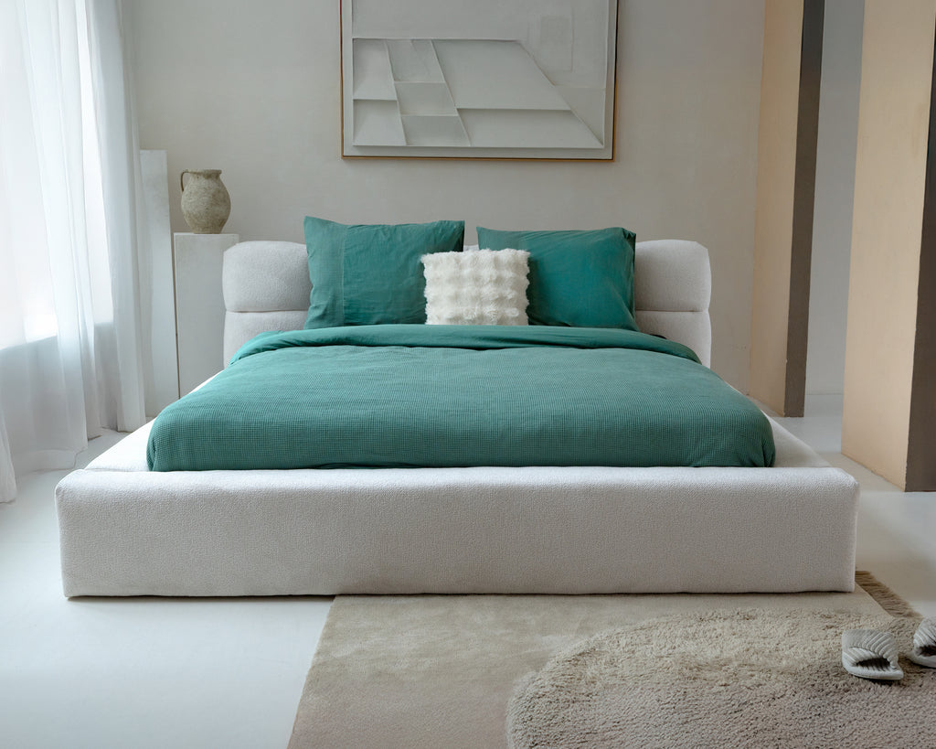 Bed met groen wafel dekbedovertrek en twee groene kussenslopen in een lichte slaapkamer