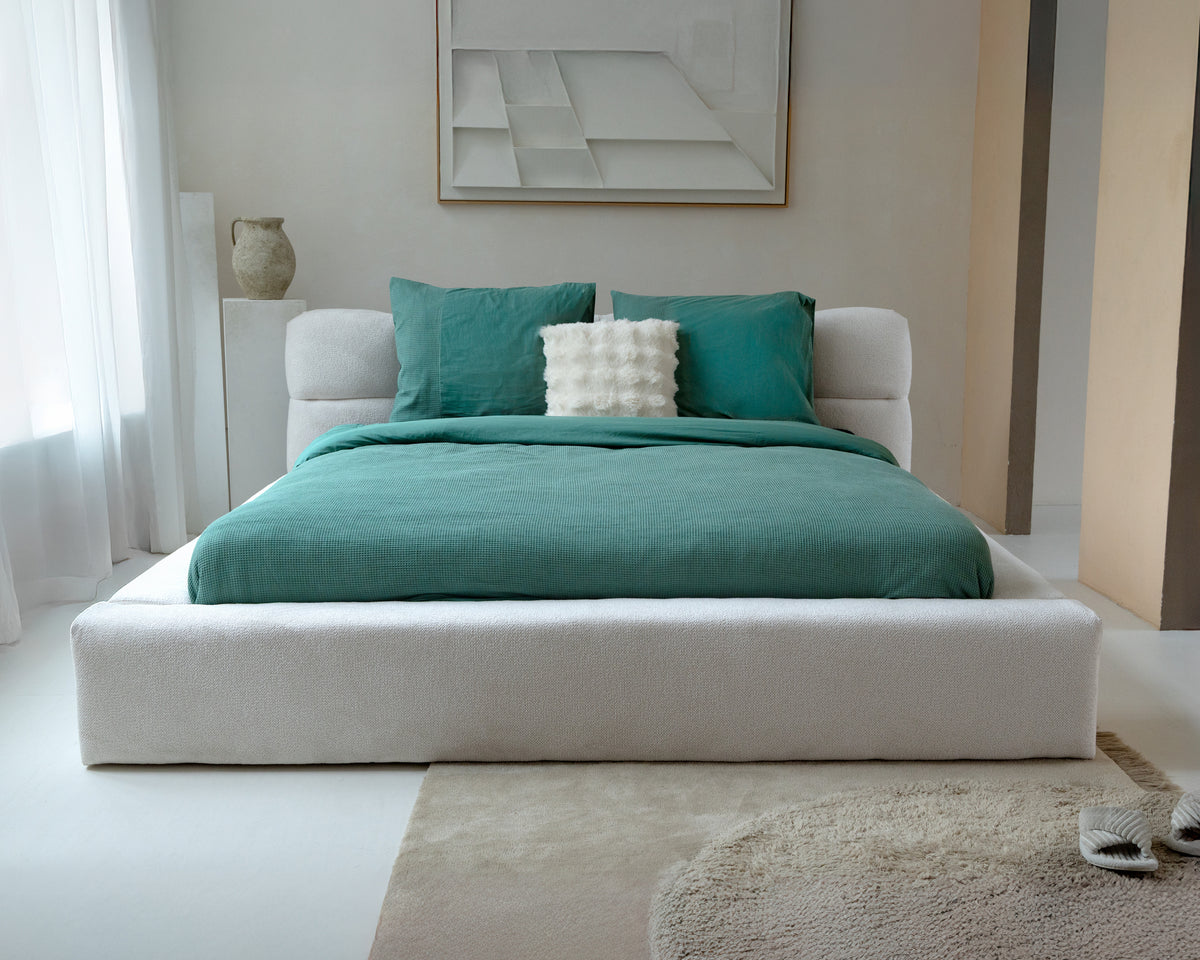 Bed met groen wafel dekbedovertrek en twee groene kussenslopen in een lichte slaapkamer