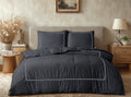 Zwart dekbedovertrek met lichte bies en twee kussens op een bed met beige hoofdbord