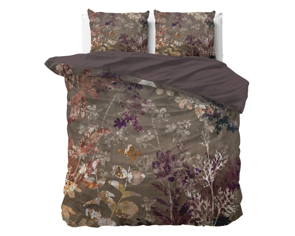 Dekbedovertrek met bloemenprint in taupe, bruin en paars op een bed met twee kussens en een effen bruine onderzijde