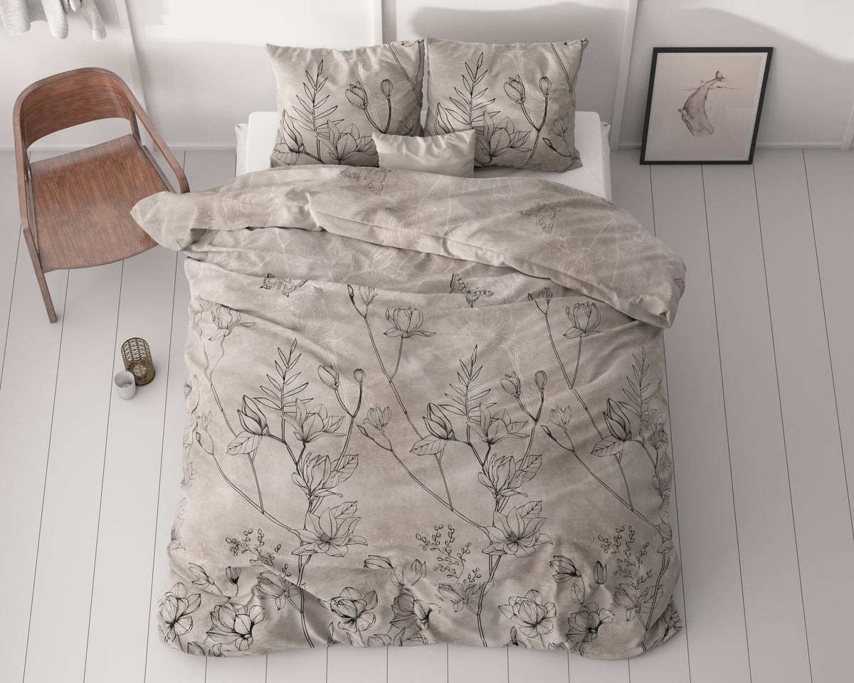 Taupe dekbedovertrek met zwarte bloemen in lijntekening op een bed, met kussens in dezelfde print