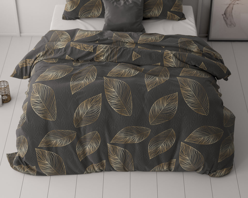 Antraciet dekbedovertrek met gouden bladprint op een bed met bijpassende kussens in een lichte slaapkamer