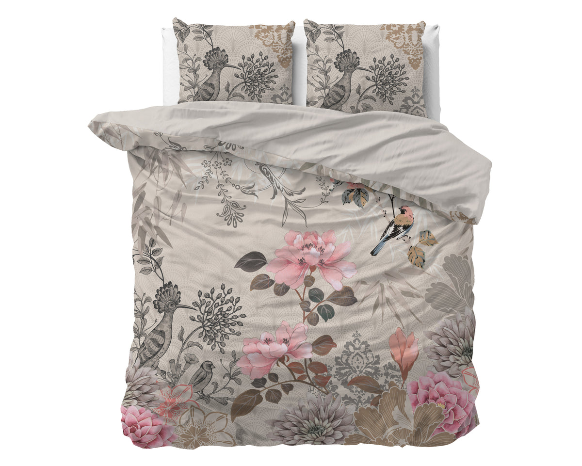 Opgemaakt bed met crème dekbedovertrek met roze bloemen en vogelprint en twee bijpassende kussens