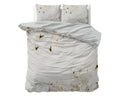 Crèmekleurig dekbedovertrek met bloemenprint en lichtgrijze achterkant, met bijpassende kussens op een bed