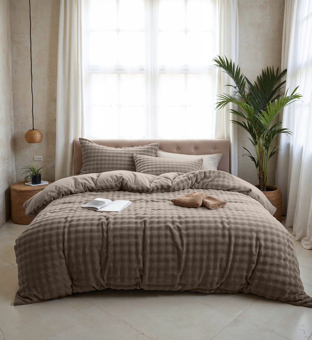 Taupe dekbedovertrek met pompon ruitstructuur en bijpassende kussenslopen op een bed in een lichte slaapkamer