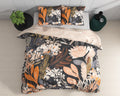 Dekbedovertrek met botanische print in oranje, perzik en crème op zwart, met twee kussens op een bed, gezien van boven