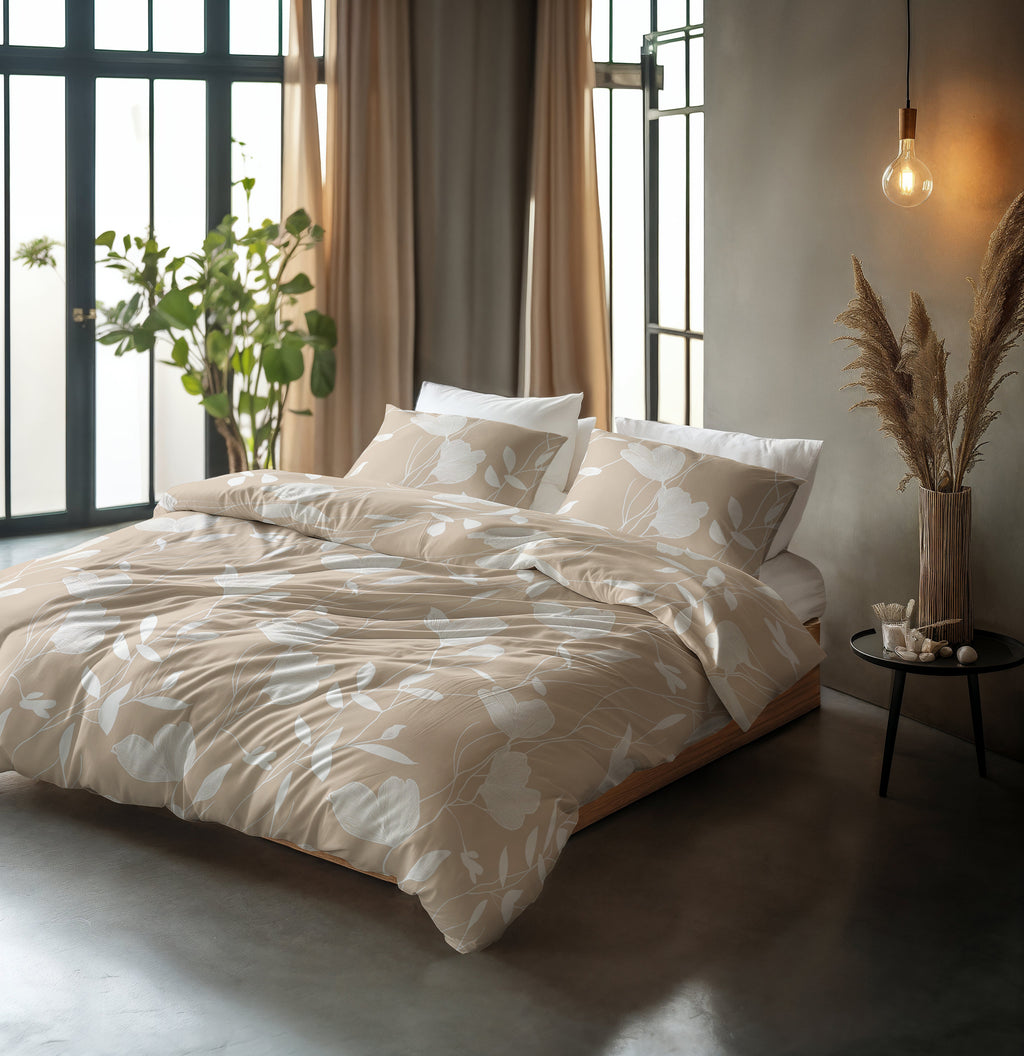 Bed met zandbeige dekbedovertrek met wit bloemendessin en bijpassende kussenslopen in een lichte slaapkamer