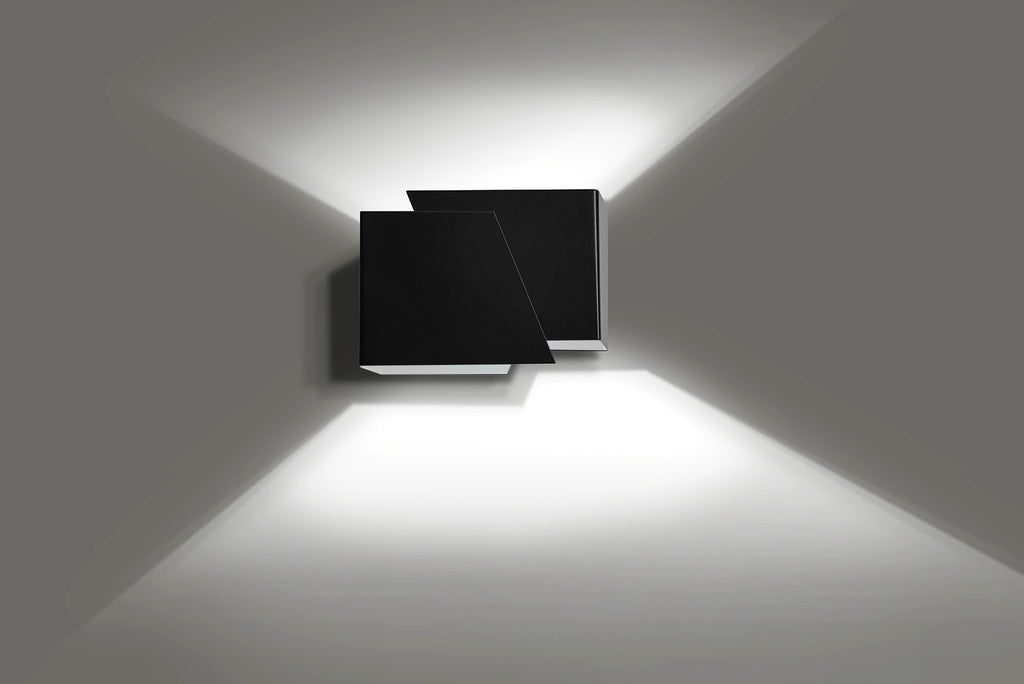 Mat zwarte wandlamp met twee hoekige vlakken die licht omhoog en omlaag over een grijze muur werpt