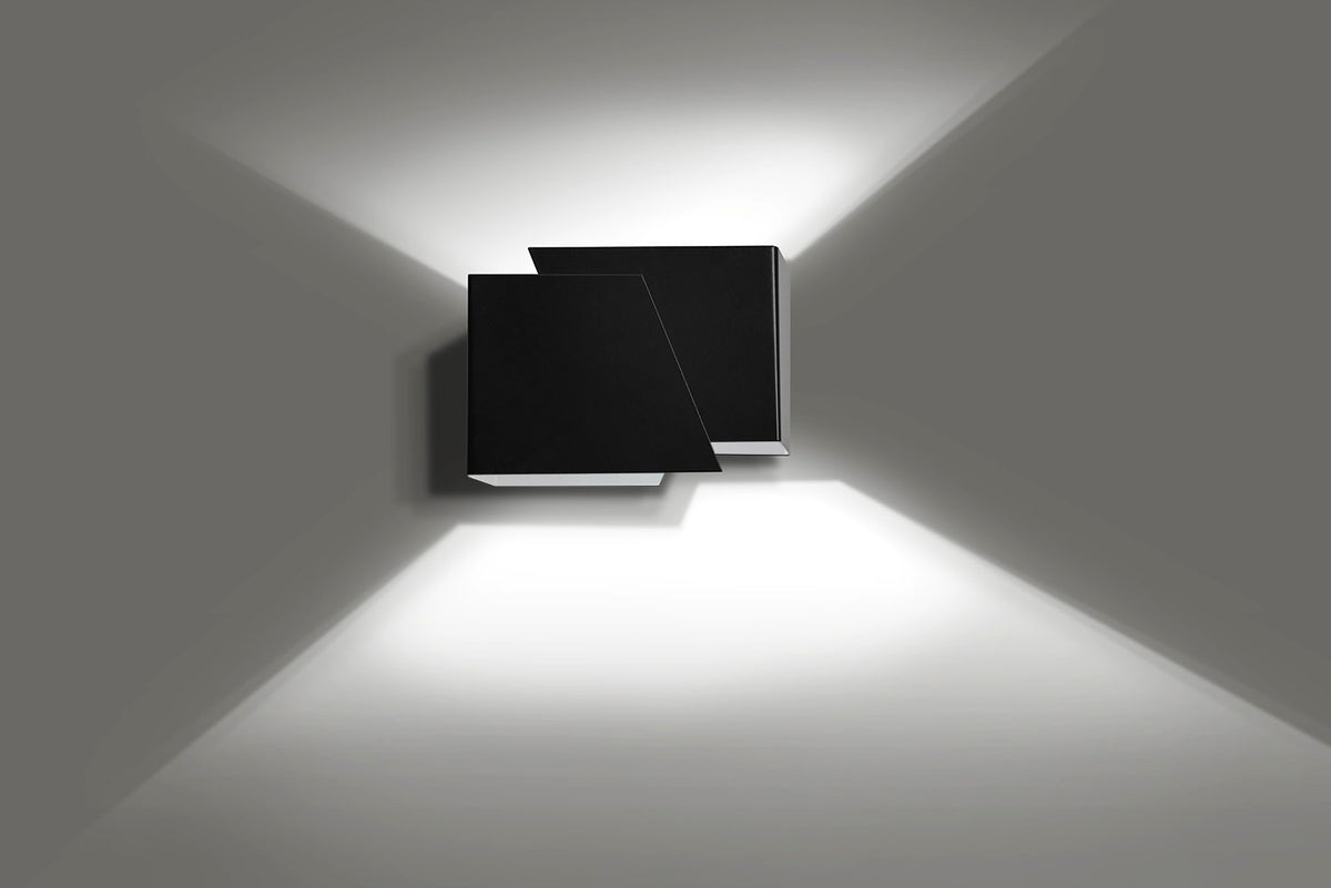 Mat zwarte wandlamp met twee hoekige vlakken die licht omhoog en omlaag over een grijze muur werpt