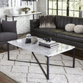 Salontafel met wit Carrara-marmeren blad en zwart X-onderstel op een wit vloerkleed voor een donkere bank
