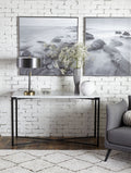 Consoletafel met wit marmeren blad en zwart metalen X-frame, met lamp en vazen, tegen een witte bakstenen muur