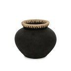 Zwarte terracotta vaas met bolle vorm en een rand van naturel raffia op een witte achtergrond
