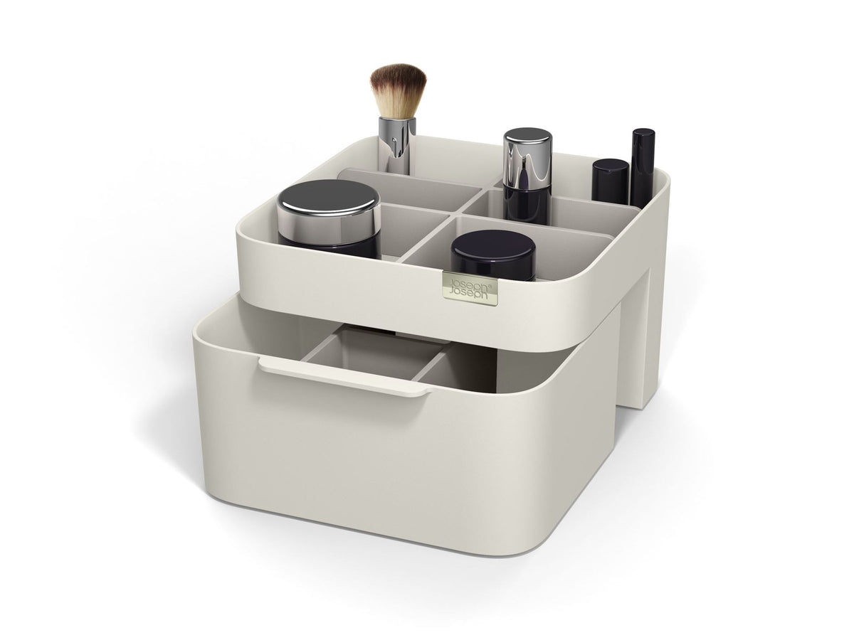 Beige make-up organizer met uitgeschoven lade en vakken met kwast, potjes en lippenstiften