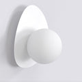 Witte wandlamp met ronde bol op een keivormige witte achterplaat tegen een lichte muur